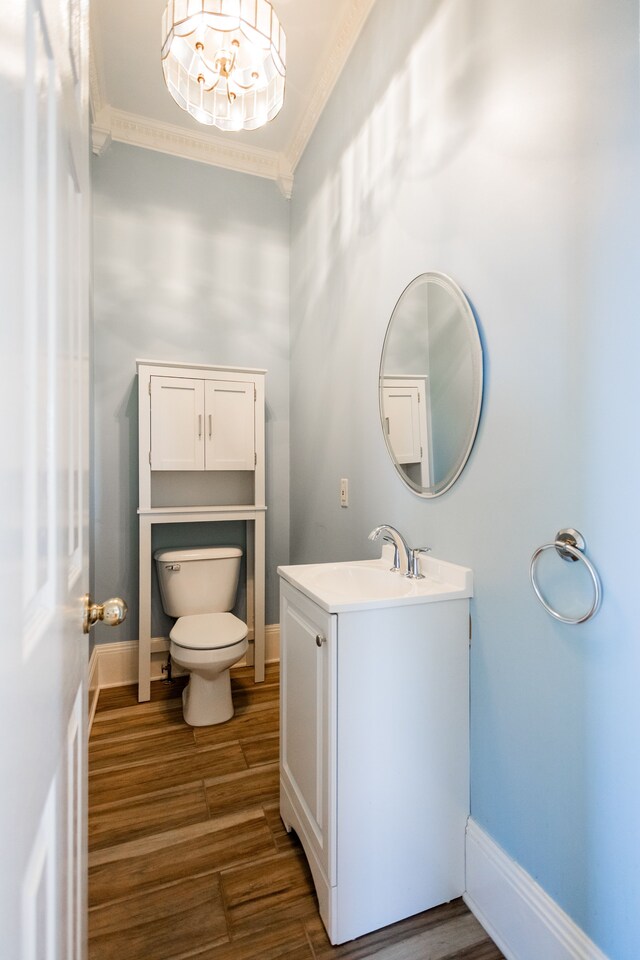 bathroom featuring toilet, ornamental molding, wood finished floors, vanity, and baseboards