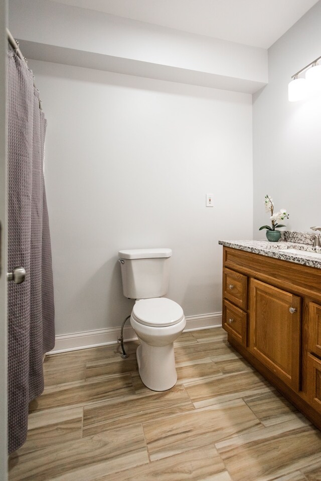 full bath featuring toilet, baseboards, vanity, wood finished floors, and a shower with curtain