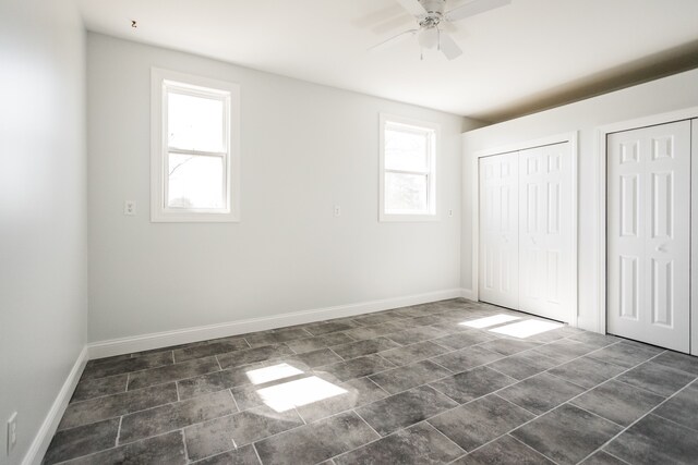 unfurnished bedroom featuring multiple closets, baseboards, and ceiling fan