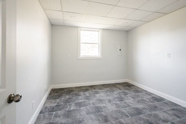 spare room with a paneled ceiling and baseboards