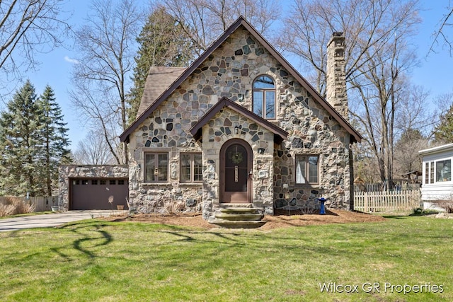 view of front facade featuring driveway, stone siding, a chimney, and fence