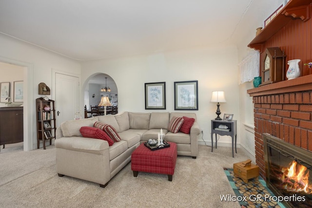 carpeted living room featuring a fireplace and arched walkways
