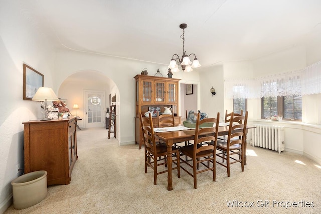 dining area featuring radiator, a chandelier, arched walkways, and light carpet
