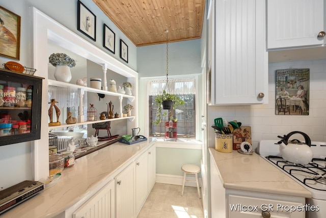 interior space featuring white gas range, white cabinets, decorative backsplash, wooden ceiling, and light stone countertops