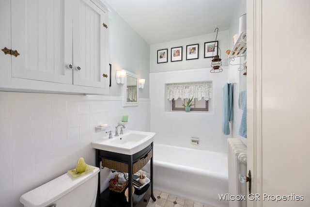 full bathroom featuring a washtub, a sink, tile walls, radiator, and toilet