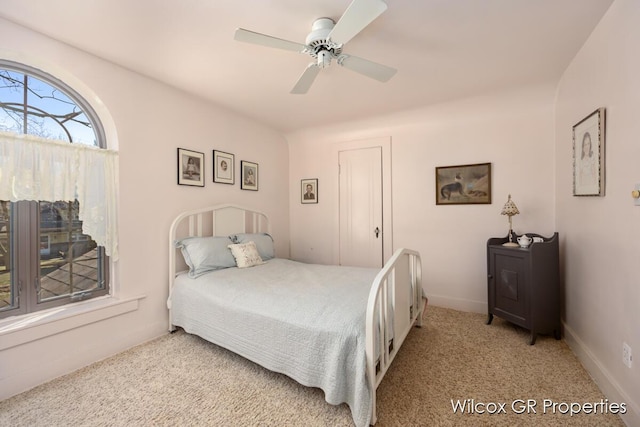 bedroom featuring light carpet, a ceiling fan, and baseboards
