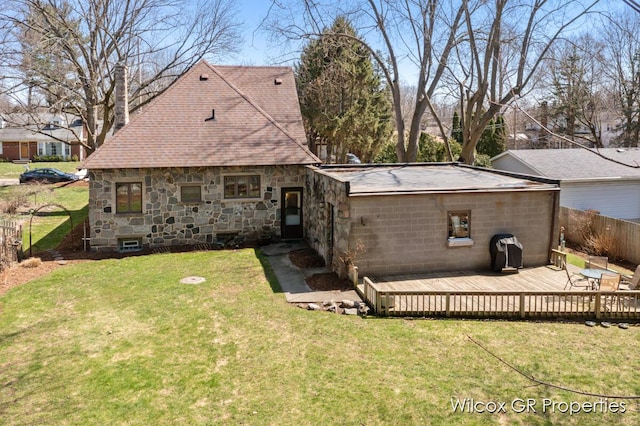 back of house with a chimney, fence, a yard, a wooden deck, and roof with shingles