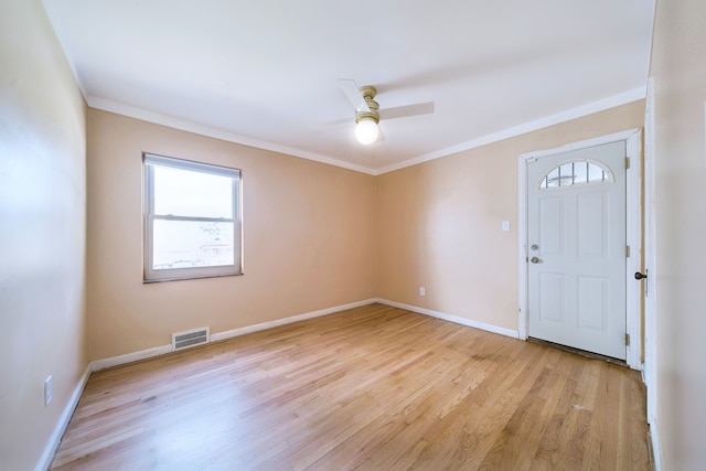 spare room featuring crown molding, ceiling fan, light wood-style flooring, and visible vents