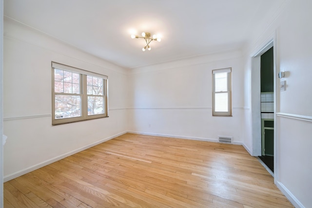 spare room featuring baseboards, visible vents, and light wood-type flooring