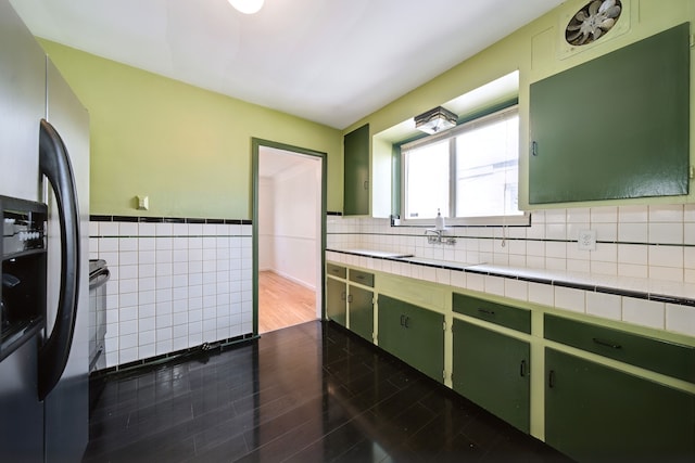 kitchen with tile countertops, tile walls, dark wood finished floors, green cabinets, and stainless steel fridge