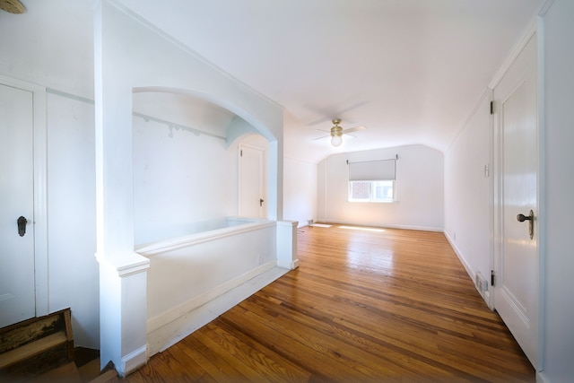 additional living space with arched walkways, a ceiling fan, wood finished floors, and lofted ceiling