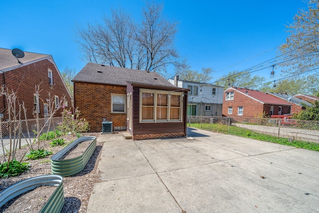 rear view of property with brick siding, a shingled roof, fence, and cooling unit