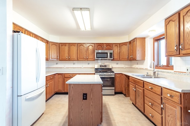 kitchen with stainless steel appliances, a sink, brown cabinets, light floors, and a kitchen island