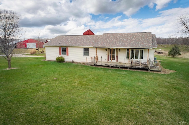 rear view of house featuring a lawn and a shingled roof