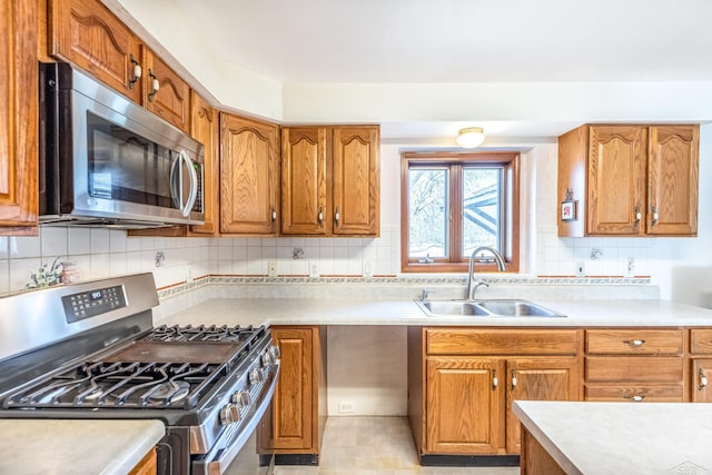 kitchen featuring brown cabinets, stainless steel appliances, light countertops, and a sink