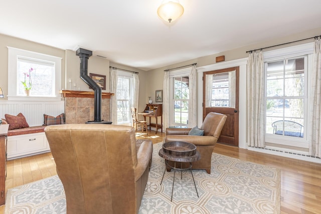 living room featuring wainscoting, light wood-style flooring, and a wood stove
