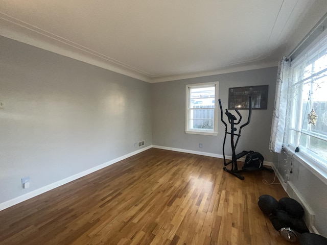 exercise area with baseboards, visible vents, dark wood finished floors, and a healthy amount of sunlight