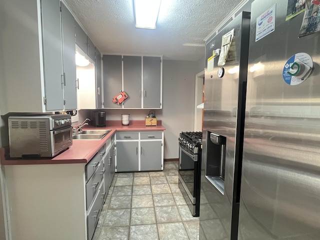 303 Sydelle Ave, Kalamazoo, MI 49006 - kitchen with stainless steel fridge, range with gas stovetop, gray cabinetry, stone finish floors, and a textured ceiling