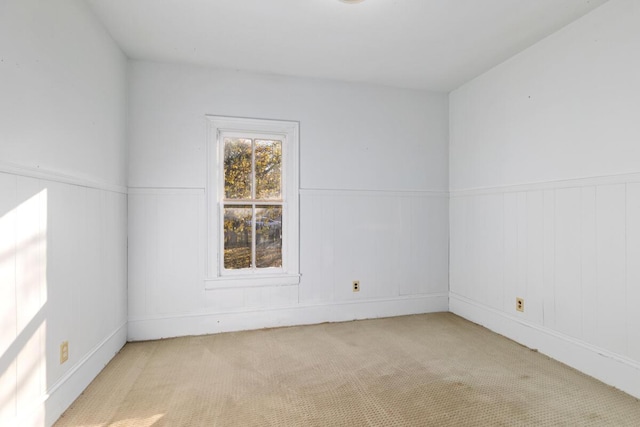 unfurnished room with carpet and wainscoting