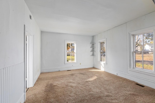 carpeted spare room featuring a healthy amount of sunlight and visible vents