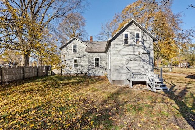 back of property featuring fence, a chimney, and a yard