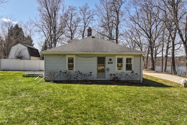 3931 S Shore Dr, Lapeer, MI 48446 - bungalow-style house with roof with shingles, a chimney, a front lawn, and fence