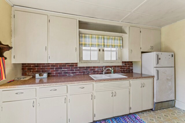 3931 S Shore Dr, Lapeer, MI 48446 - kitchen featuring freestanding refrigerator, white cabinetry, decorative backsplash, and a sink