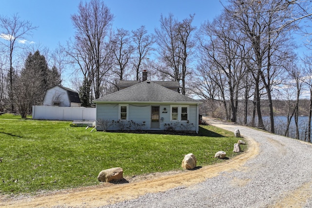 3931 S Shore Dr, Lapeer, MI 48446 - view of front of house featuring gravel driveway, a chimney, fence, a shingled roof, and a front lawn