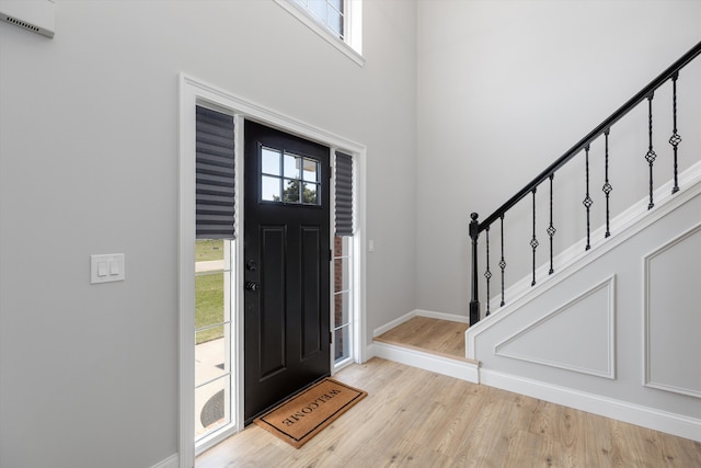 foyer with wood finished floors, baseboards, stairs, and a healthy amount of sunlight