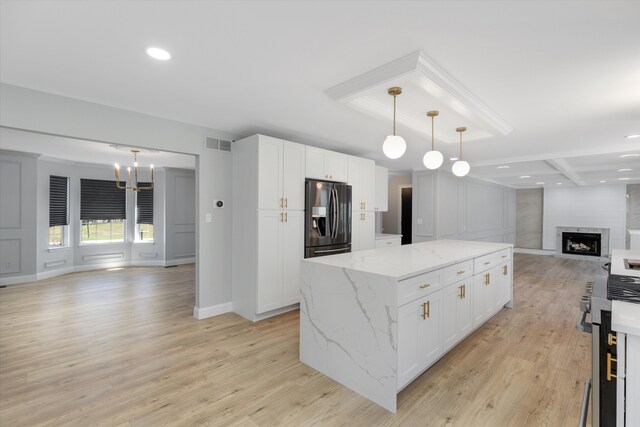 kitchen featuring open floor plan, fridge with ice dispenser, white cabinets, visible vents, and a kitchen island