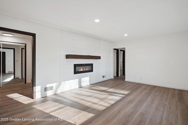 unfurnished living room with visible vents, baseboards, recessed lighting, wood finished floors, and a large fireplace