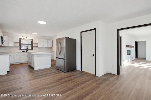 kitchen featuring open shelves, a sink, stainless steel appliances, light countertops, and white cabinets