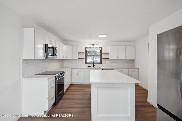 kitchen with white cabinets, open shelves, a sink, tasteful backsplash, and appliances with stainless steel finishes