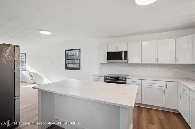 kitchen featuring decorative backsplash, stainless steel appliances, white cabinetry, light stone countertops, and dark wood-type flooring