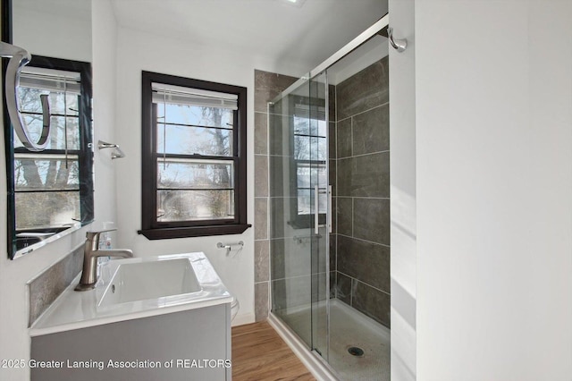 full bath featuring wood finished floors, vanity, and a stall shower