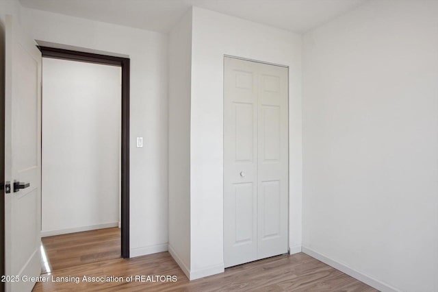 unfurnished bedroom with light wood-style floors, a closet, and baseboards