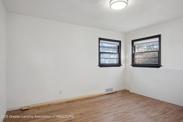 empty room featuring wood finished floors and visible vents
