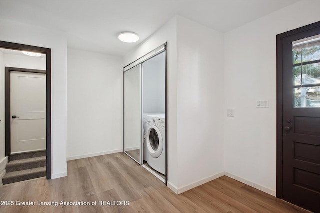 clothes washing area with laundry area, baseboards, light wood-style floors, and washer / clothes dryer