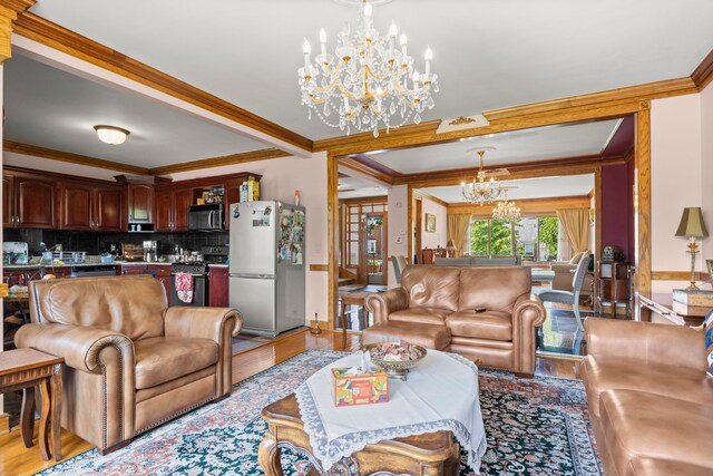 living room with ornamental molding, a chandelier, and light wood-type flooring
