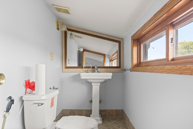 bathroom featuring a sink, baseboards, toilet, tile patterned flooring, and visible vents
