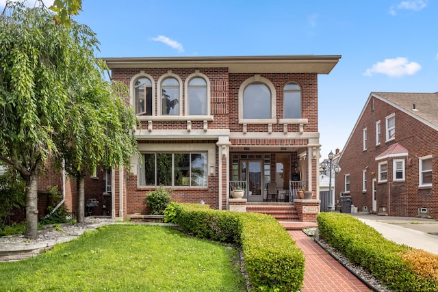 rear view of property featuring a porch, brick siding, and a yard