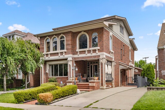 view of front of home featuring a gate, concrete driveway, board and batten siding, a porch, and brick siding