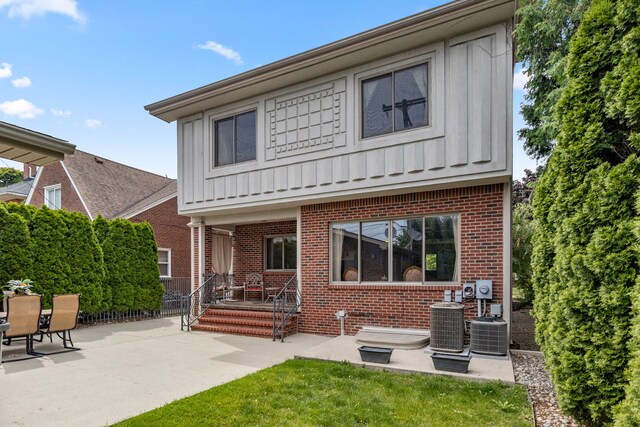 back of property with brick siding, board and batten siding, a patio, and central AC unit