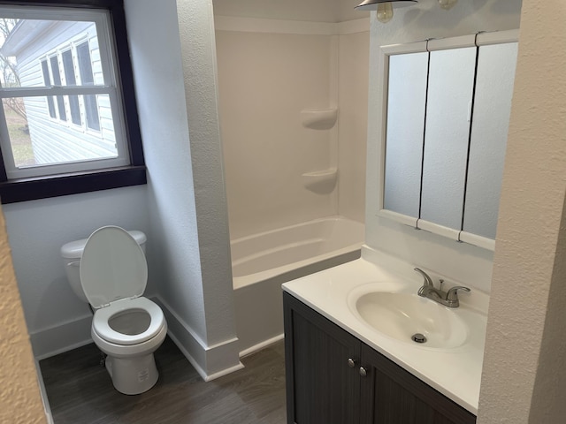 bathroom with wood finished floors, vanity, shower / tub combination, baseboards, and toilet