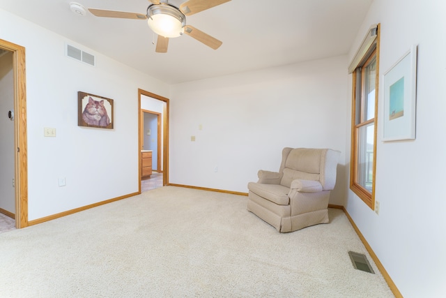 sitting room featuring visible vents, baseboards, and light carpet