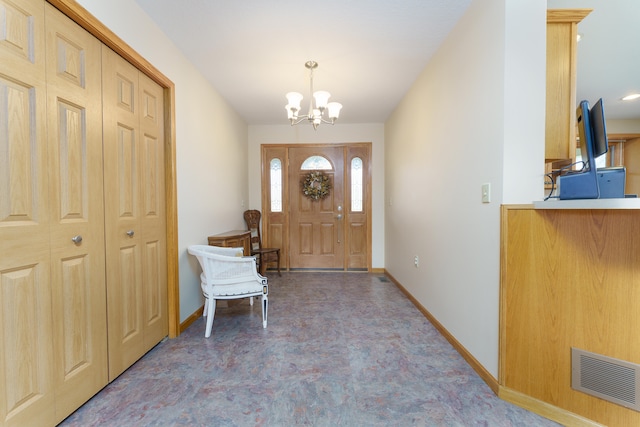 foyer entrance with baseboards, a chandelier, and visible vents