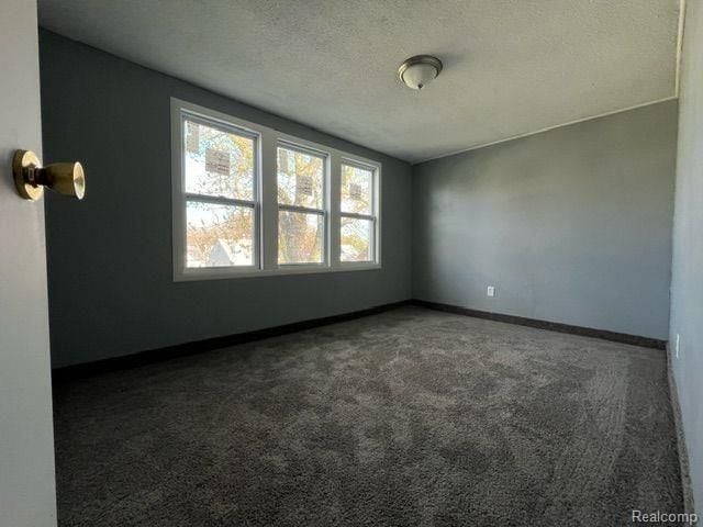 empty room with baseboards, carpet floors, and a textured ceiling