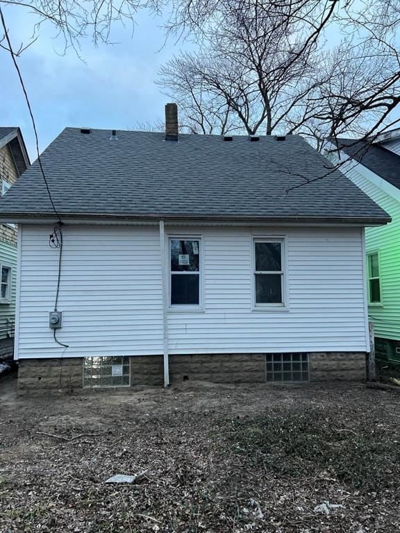 back of property featuring a chimney and a shingled roof