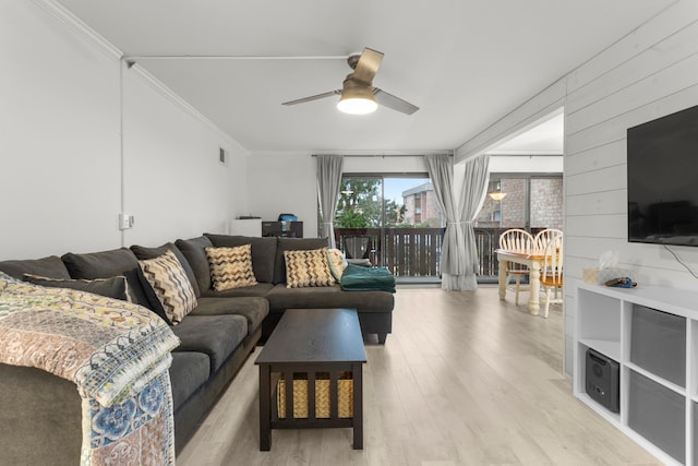 living room featuring visible vents, light wood-style floors, ceiling fan, crown molding, and wooden walls