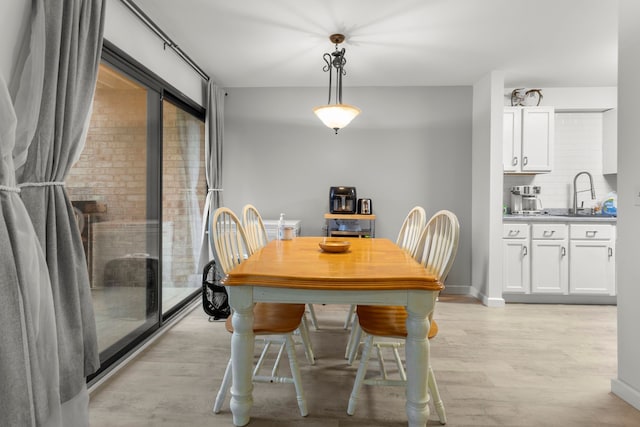 dining area with light wood-type flooring and baseboards